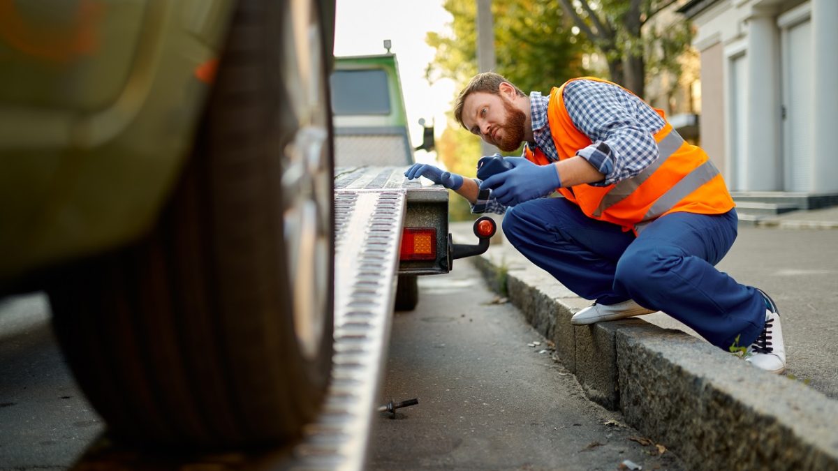 Towing service driver assisting a car onto a flatbed tow truck in Orlando FL