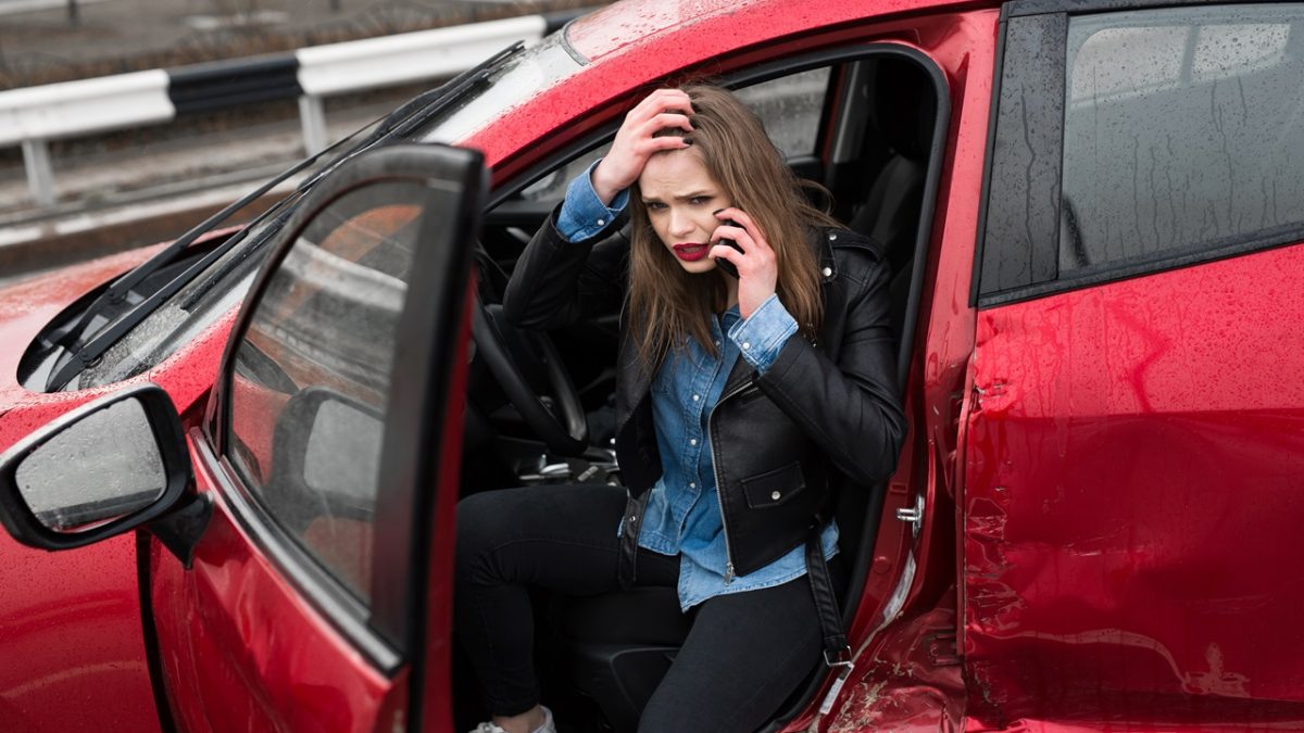 Woman calling for roadside help after accident in red SUV