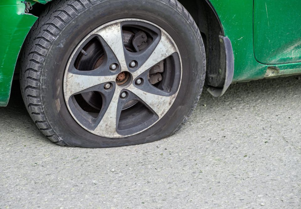green car with a flat tire